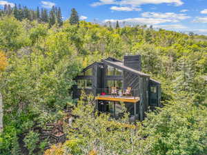 Rear view of house with a forest view, a chimney, and a wooden deck