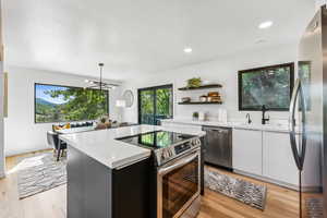 Kitchen featuring stainless steel appliances, light countertops, white cabinets, open shelves, and recessed lighting
