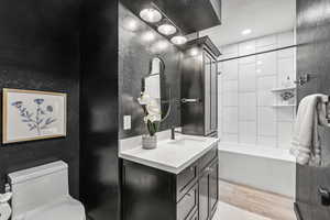 Full bath with vanity, wood finished floors, and shower / bath combination
