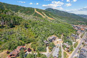 Aerial view of property and surrounding area featuring a mountain backdrop and nearby suburban area