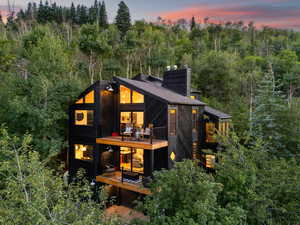 Back of property at dusk with a chimney and a balcony
