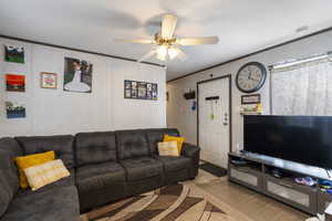 Tiled living area featuring crown molding and a ceiling fan