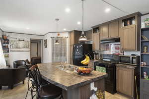 Kitchen with black appliances, open shelves, dark countertops, under cabinet range hood, and a kitchen bar