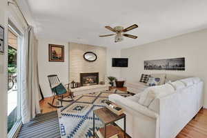 Living room with ceiling fan, wood finished floors, and a fireplace