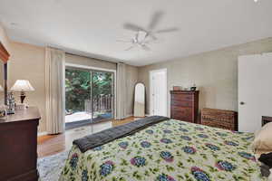 Bedroom with access to exterior, wood finished floors, and a ceiling fan