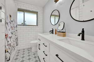 Full bathroom featuring double vanity, tile patterned floors, and a shower with curtain