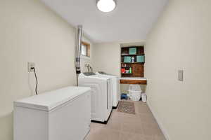 Laundry room featuring washing machine and clothes dryer and light tile patterned floors