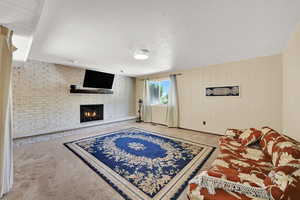 Carpeted living room featuring a fireplace and wooden walls