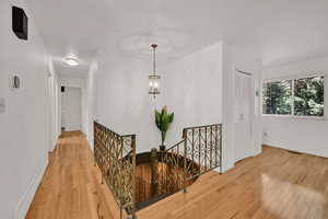 Corridor with an upstairs landing and wood finished floors