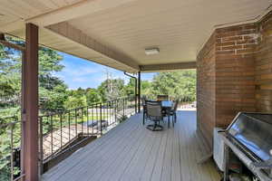 Wooden terrace with outdoor dining area and view of wooded area