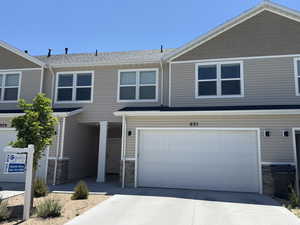 View of front of home with stone siding, a garage, and driveway
