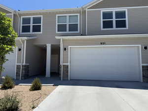 View of front of house with stone siding, an attached garage, and driveway
