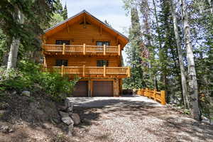 View of front of house featuring a balcony, gravel driveway, and a garage