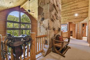 Hall with wood ceiling, wood walls, carpet, and an upstairs landing
