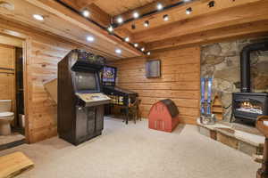 Recreation room featuring carpet, a wood stove, wooden walls, and recessed lighting