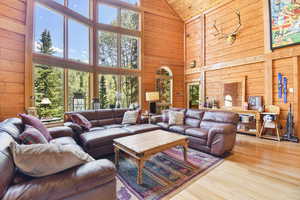 Living room featuring high vaulted ceiling, wood walls, wood finished floors, and wooden ceiling