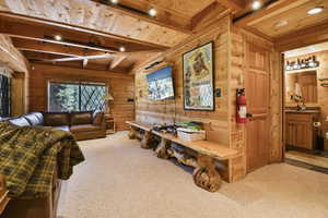Living room with a wooden ceiling with exposed beams, wooden walls, and carpet floors