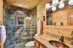 Bathroom with vanity, a shower stall, wood walls, and wood ceiling