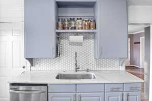 Updated Kitchen featuring grey cabinets, quartz countertops, stainless steel appliances, decorative backsplash, LVP flooring, and ornamental molding
