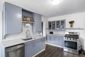 Updated Kitchen featuring grey cabinets, quartz countertops, stainless steel appliances, decorative backsplash, LVP flooring, and ornamental molding