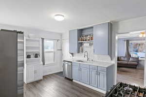 Updated Kitchen featuring grey cabinets, quartz countertops, stainless steel appliances, decorative backsplash, LVP flooring, and ornamental molding