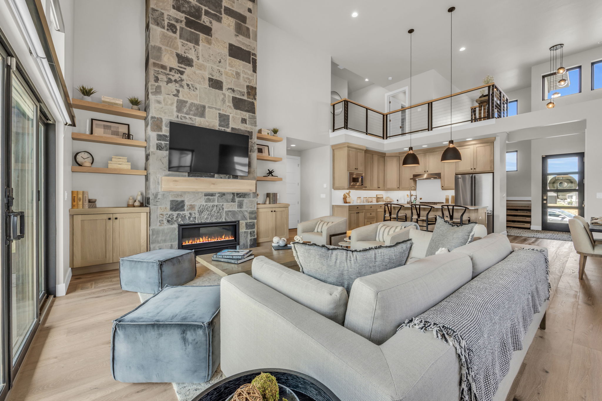 Living area featuring a high ceiling, a fireplace, light wood-type flooring, and recessed lighting