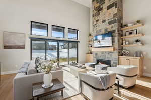 Living area with light wood-type flooring, a fireplace, and a high ceiling