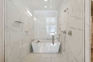 Full bathroom with tile walls, a freestanding tub, a marble finish shower, and recessed lighting