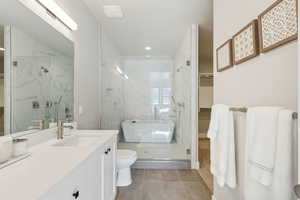 Bathroom with a marble finish shower, a walk in closet, tile patterned flooring, vanity, and recessed lighting