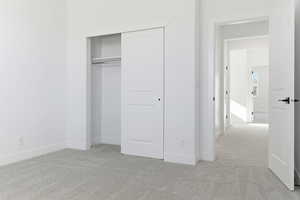 Unfurnished bedroom with light carpet and a closet