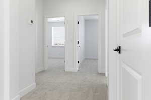 Corridor with light colored carpet and baseboards
