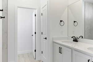 Bathroom featuring double vanity and light wood finished floors