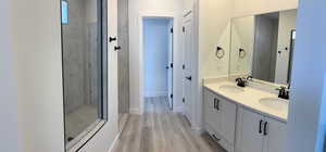 Bathroom featuring a marble finish shower, double vanity, and LVP floors