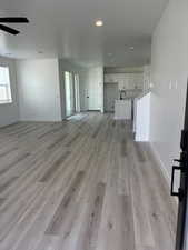 Unfurnished living room featuring light LVP flooring, ceiling fan.
