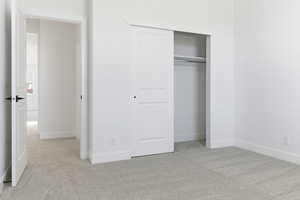 Unfurnished bedroom with light colored carpet and a closet