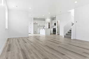 Unfurnished living room featuring stairway, light wood finished floors, and recessed lighting
