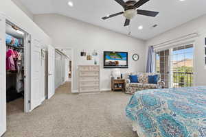Bedroom with vaulted ceiling, light carpet, a spacious closet, access to exterior, and ceiling fan