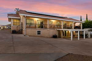 Back of house featuring a balcony, solar panels, a tile roof, and stucco siding