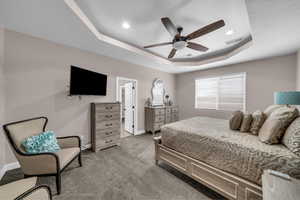 Bedroom featuring a raised ceiling, light carpet, a ceiling fan, and recessed lighting