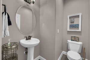 Half bathroom with toilet and baseboards