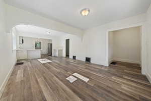 Unfurnished living room featuring dark wood finished floors and arched walkways