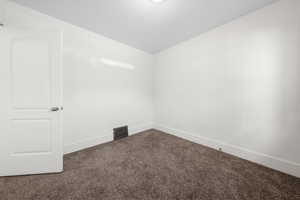 Empty room with carpet and vaulted ceiling