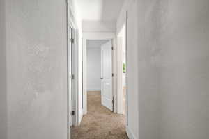 Hallway with carpet floors and a textured wall