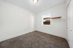 Empty room with dark carpet and baseboards