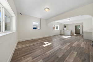 Unfurnished living room featuring arched walkways and wood finished floors