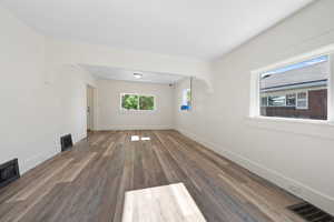 Unfurnished living room with arched walkways and wood finished floors