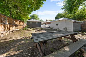 Fenced backyard featuring a deck and an outbuilding