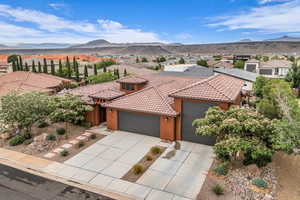 View of front of house featuring an attached garage, a tiled roof, a mountain view, stucco siding, and concrete driveway