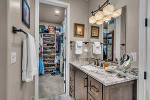 Bathroom with vanity, a walk in closet, and wood finished floors