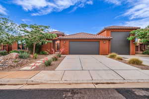 View of front of home featuring an attached garage, a tile roof, stucco siding, and concrete driveway